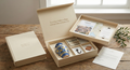 Open beige gift box with handmade italian gifts on a wooden surface.